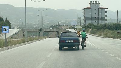 Hatay’ın Defne ilçesinde, bisikletli çocuğun trafikte seyir halindeki otomobile tutunarak