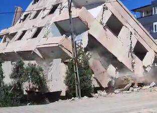 Hatay’ın Antakya ilçesinde ağır hasarlı bir bina, iş makinesinin müdahalesiyle