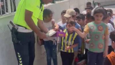 Hatay’da polis ekiplerinin okul önünde sıra bekleyen öğrencilere çikolata dağıtması,