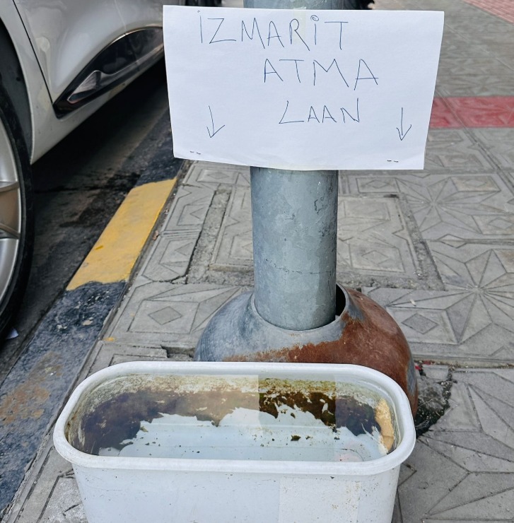 İskenderun’un işlek caddelerinden birinde, sokak hayvanlarına su veren bir esnaf,